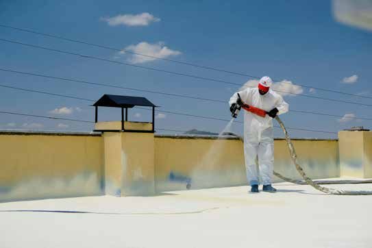 Worker spraying waterproofing coating on a rooftop